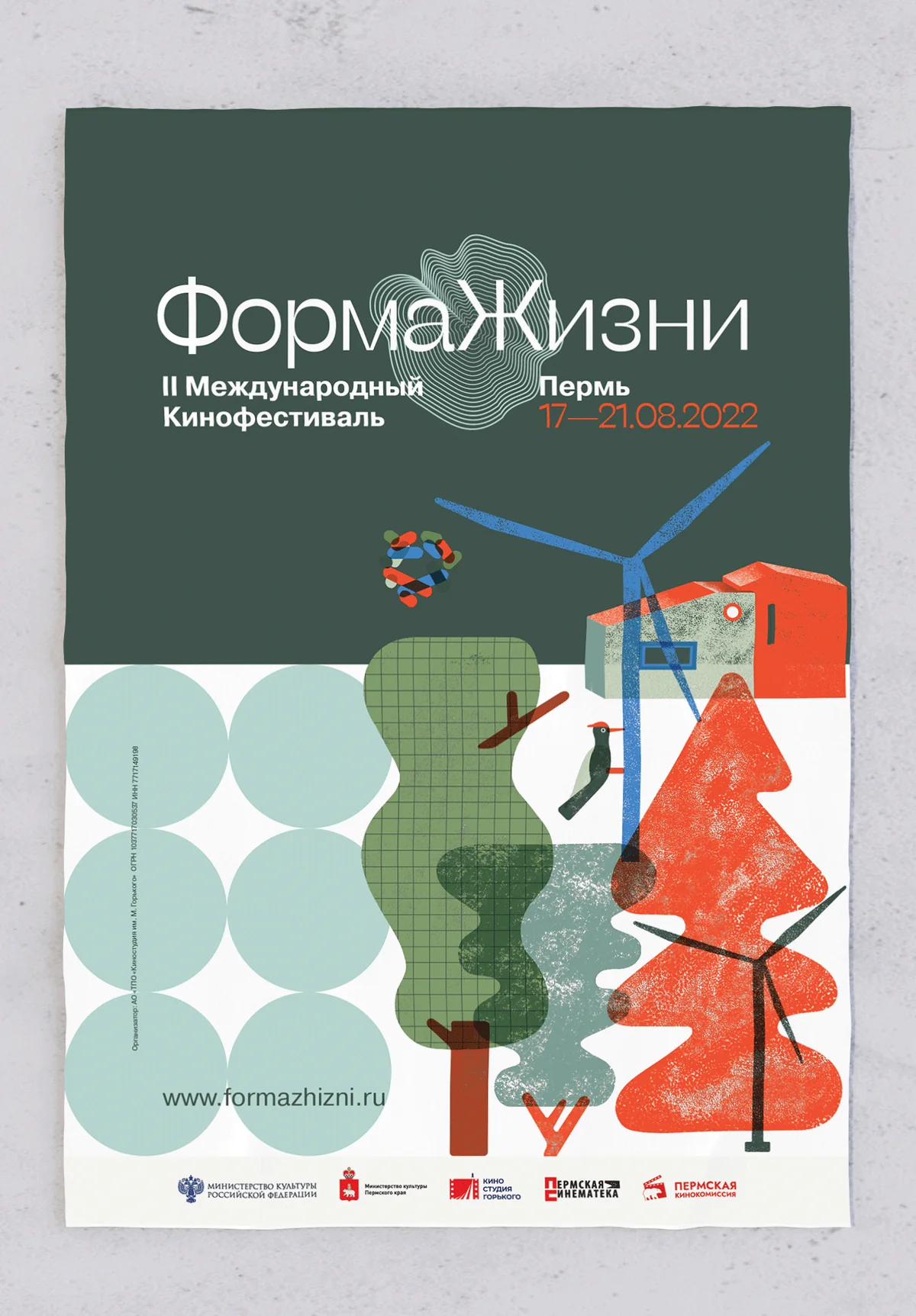 The 2022 poster: a dark forest-green field above with the white wordmark and the dates 17—21.08.2022, a white field below carrying a wind turbine, a red house and textured trees, with a grid of pale green circles at the lower left.